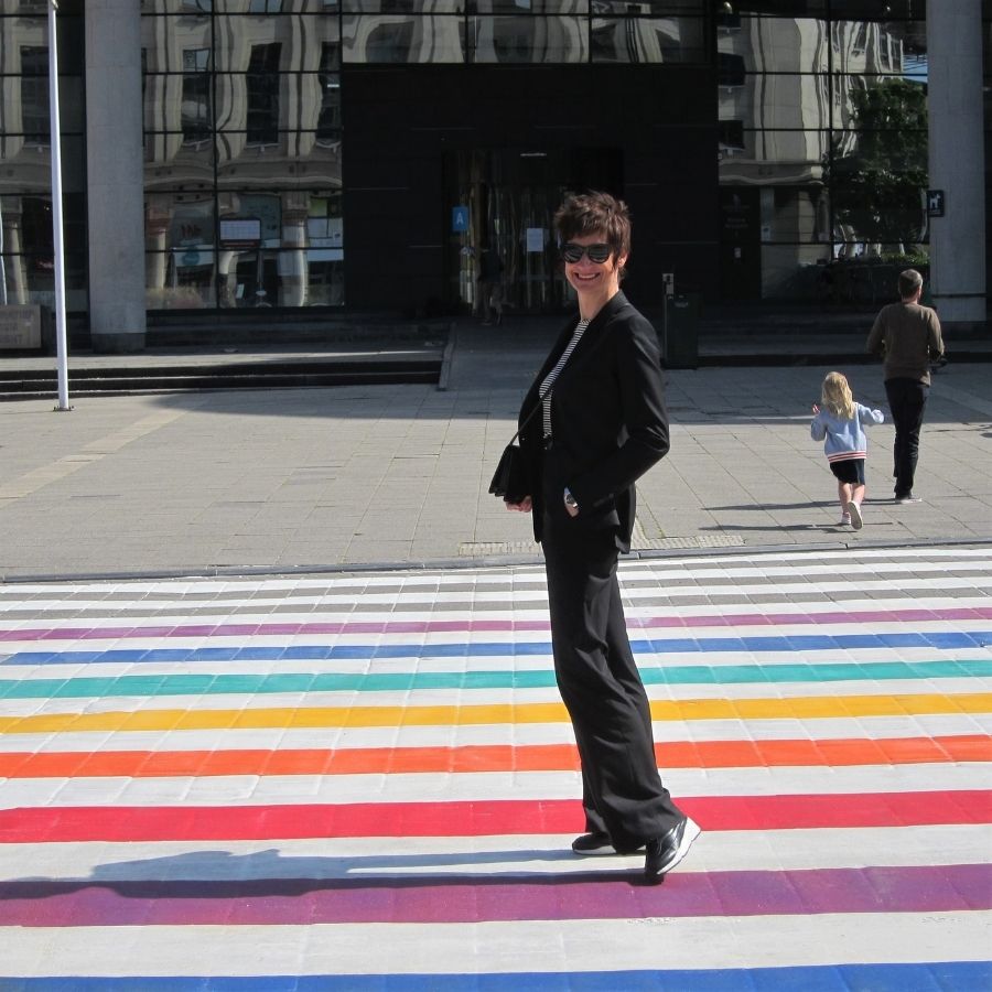 maatpak dames - zwart tweedelig in fijne wollen stof geposeerd op een regenboog voetpad