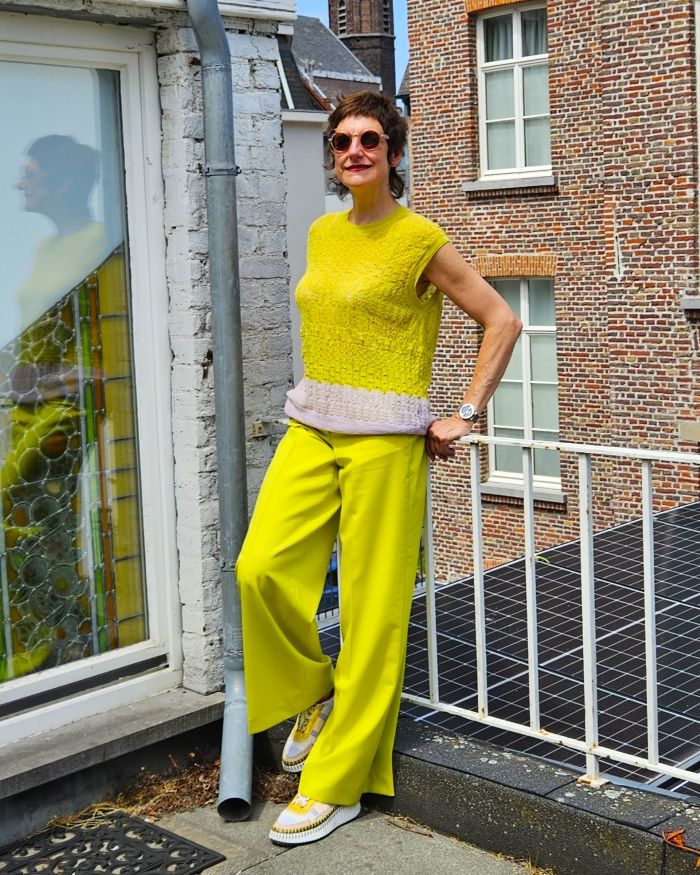 limoengele damesbroek op maak, ton-sur-ton gecombineerd met limoengele mouwloze tricot truitje met lichtpaarse zoom, en lichtkleurige sneakers met limoengeel accent